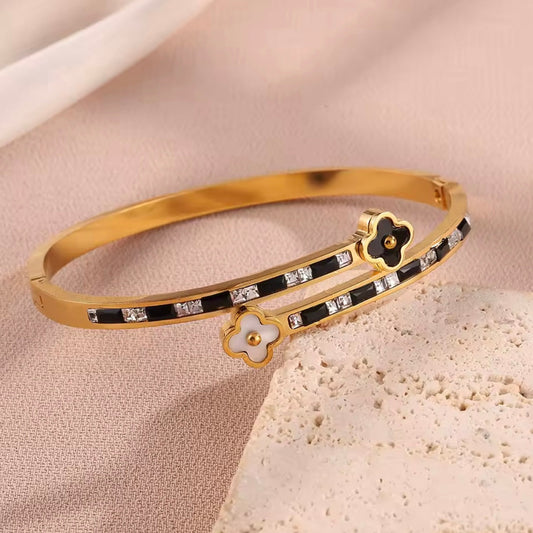 Gold bracelet with black and white accents on a beige surface