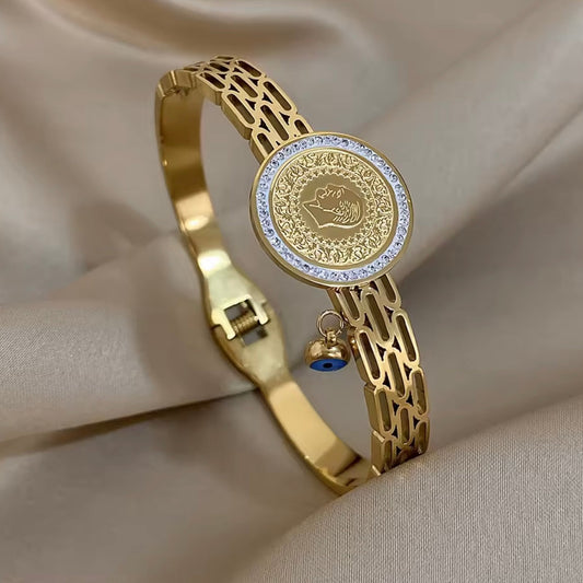 Gold bracelet with intricate design and decorative elements on a beige fabric background