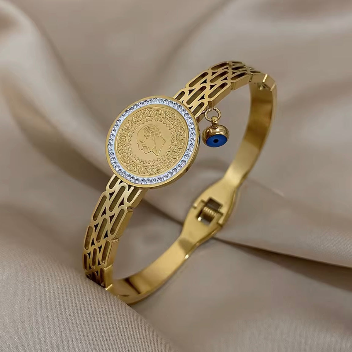 Gold bracelet with a coin charm on a beige fabric background