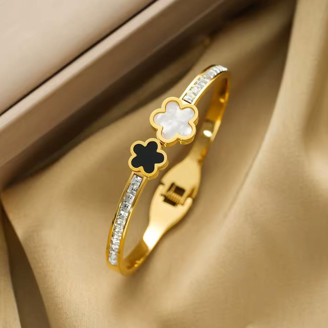 Gold bracelet with floral designs on a beige fabric background