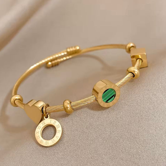 Gold bracelet with green gemstone on a beige background