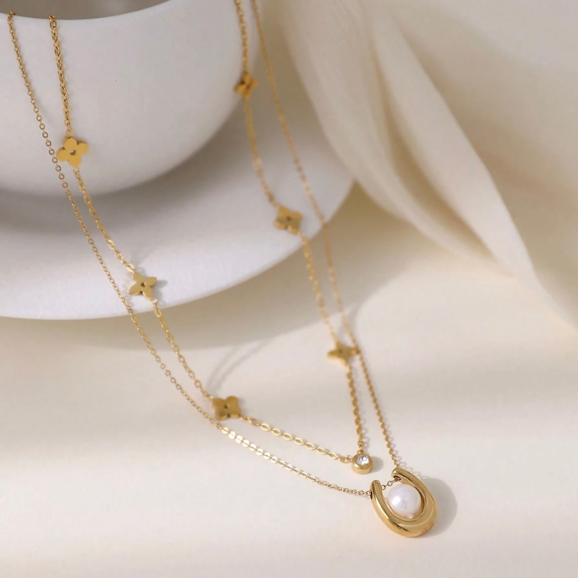 Gold necklaces with floral and circular pendants on a white surface