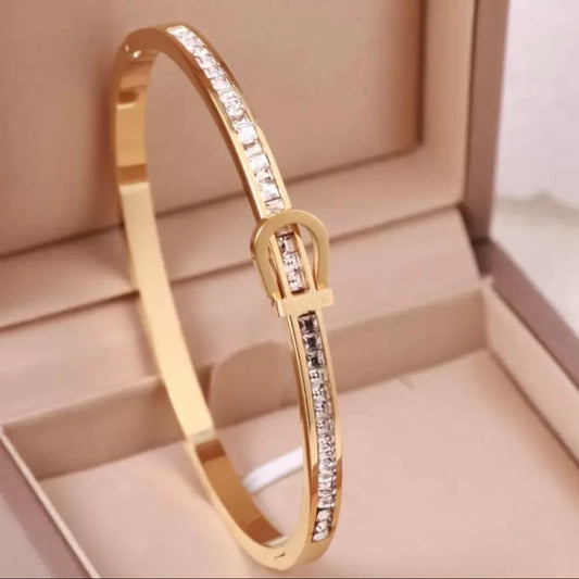 Gold bracelet with diamond accents on a beige jewelry box