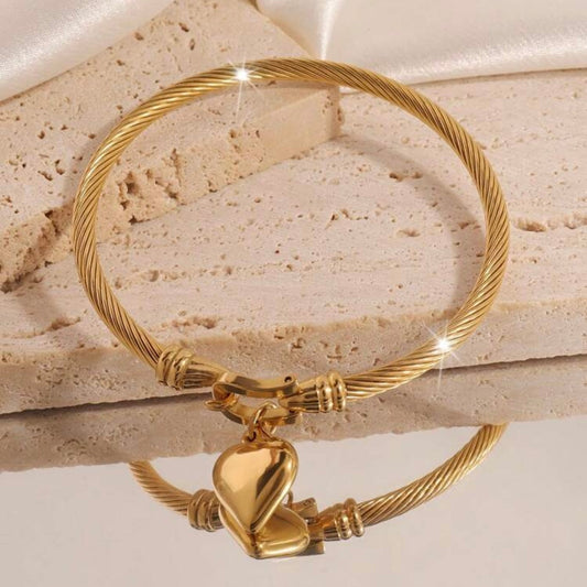 Gold bracelet with a heart-shaped charm on a stone surface