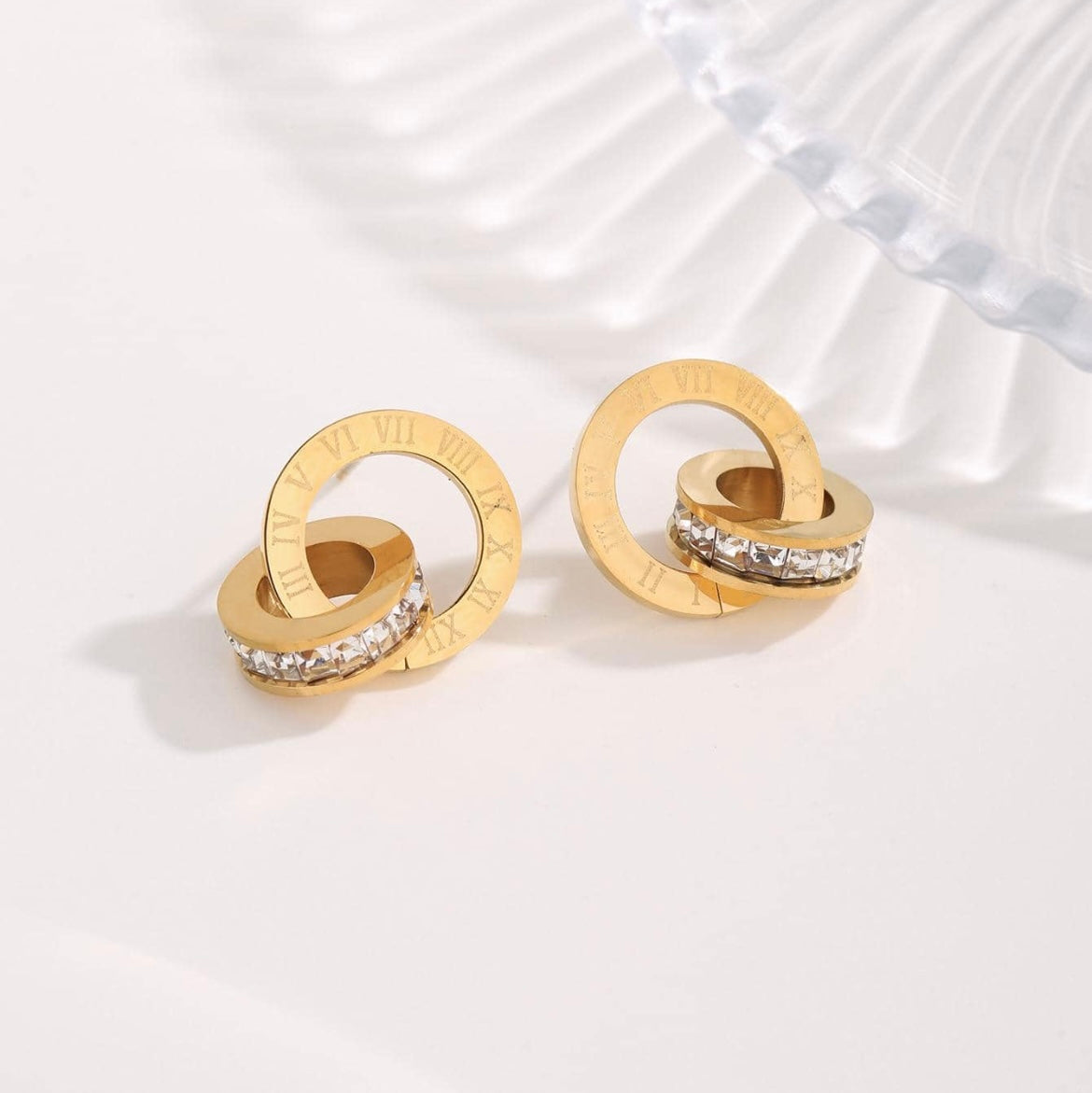 Gold hoop earrings with embedded stones on a light background