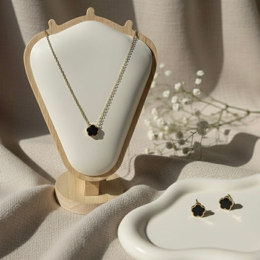 Necklace and earrings on a white cushion with a beige background