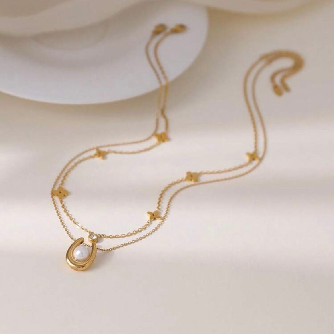 Gold necklace with a pearl pendant on a light beige background