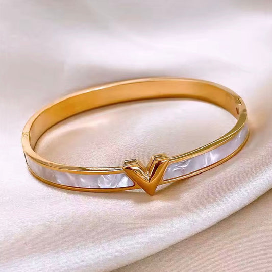 Gold bracelet with a heart-shaped clasp on a white background