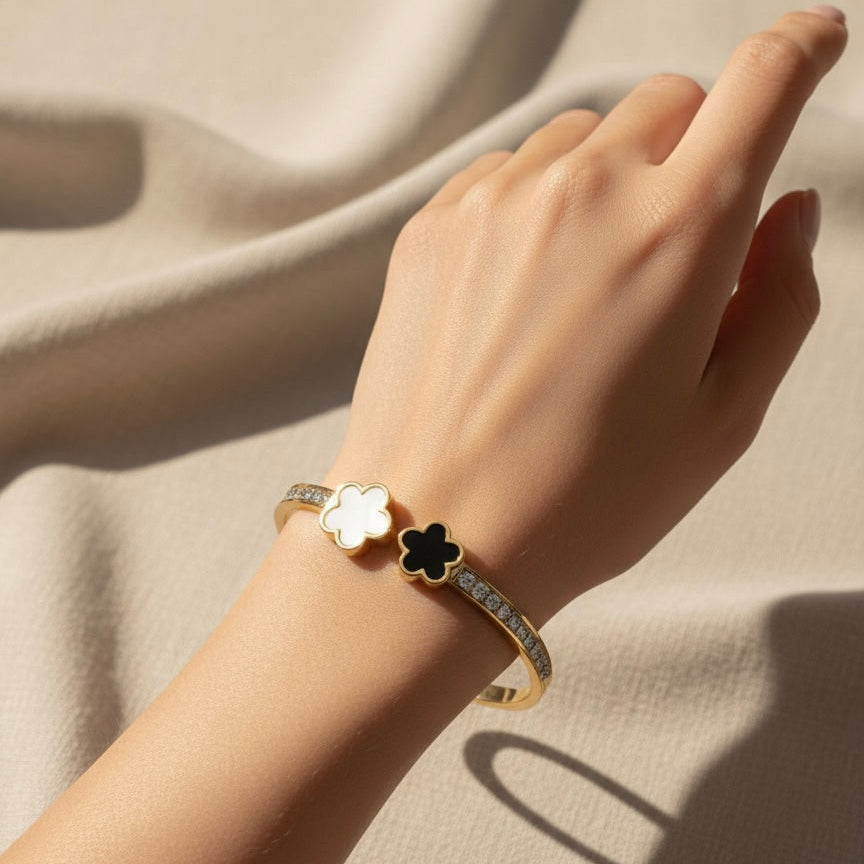 Hand wearing a bracelet with a flower design on a beige fabric background