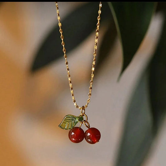Necklace with cherry pendant on a blurred natural background