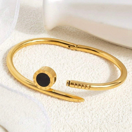 Gold bracelet with a black stone on a white textured surface