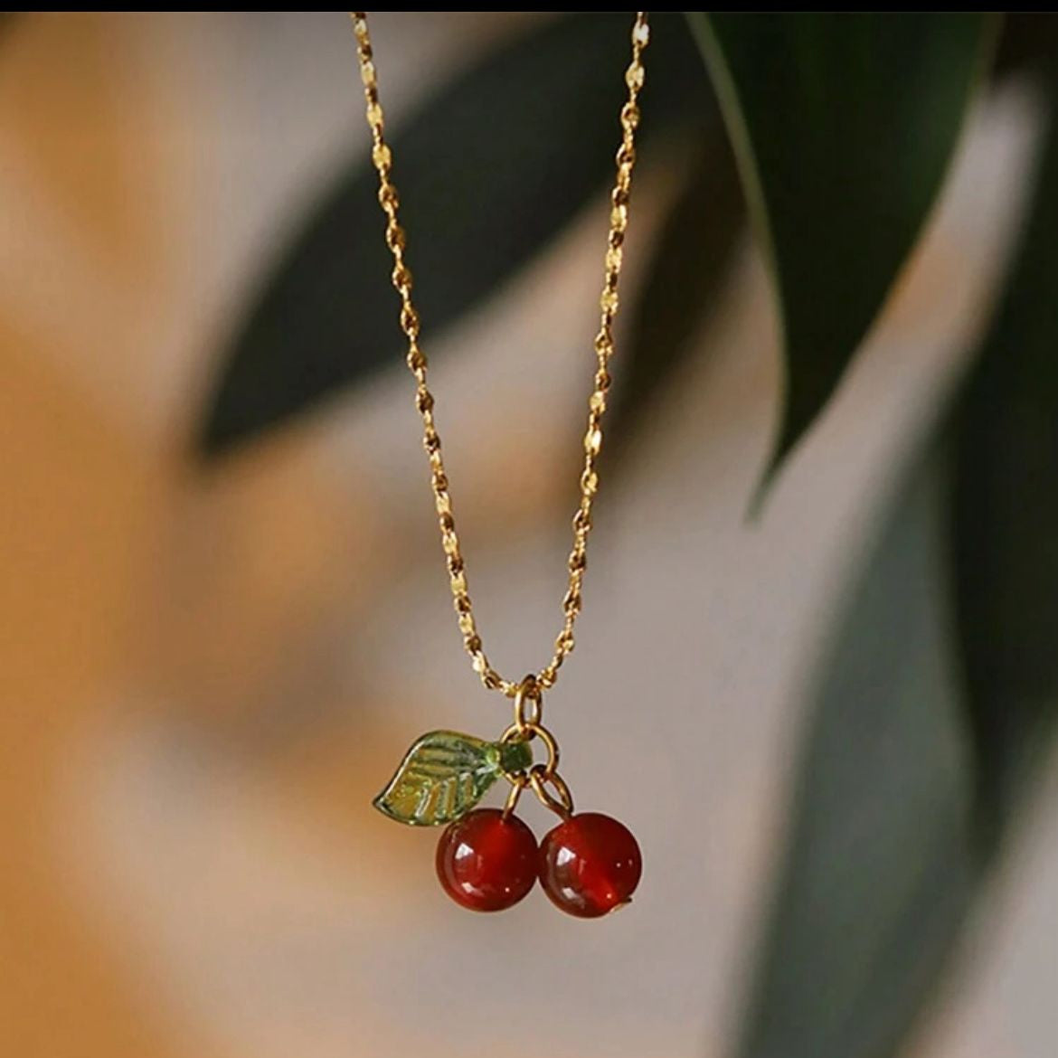 Necklace with cherry pendant on a blurred natural background