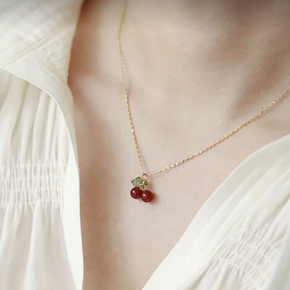 Necklace with a heart pendant worn by a person in a white outfit.